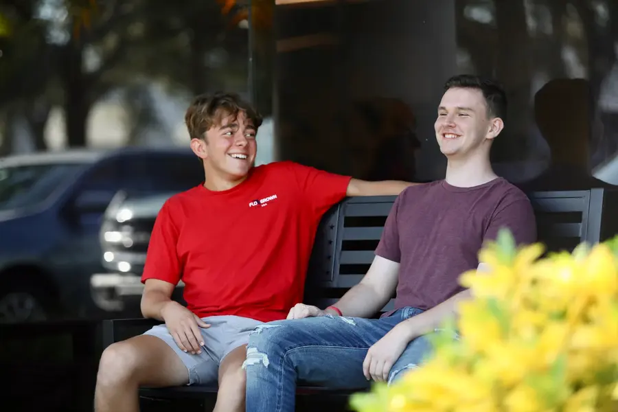 Two students talking on a bench outside the Naples campus