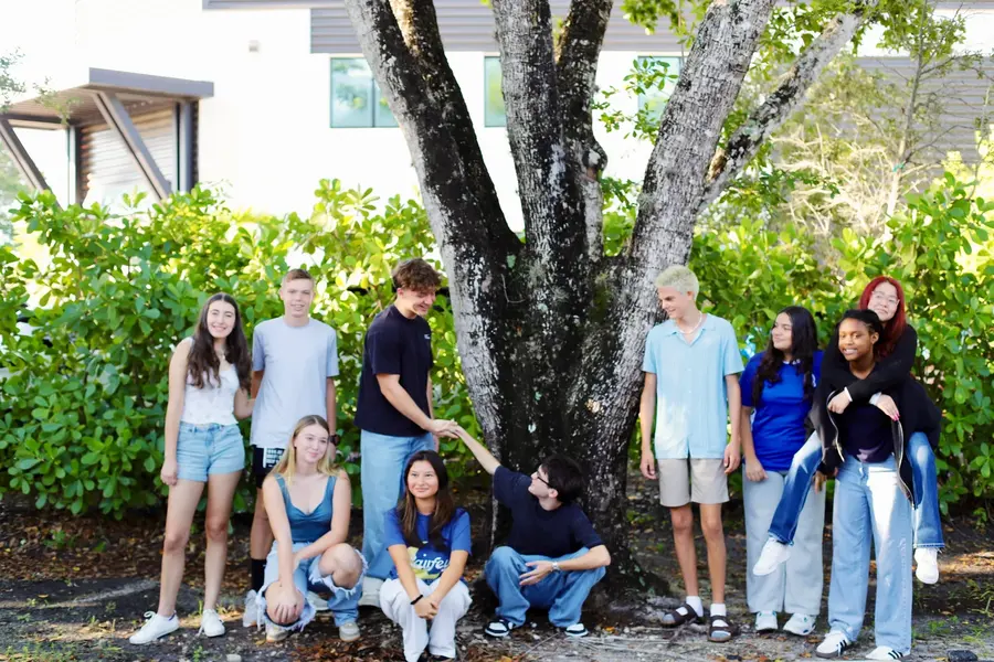 A group of Freedom students under a tree on campus