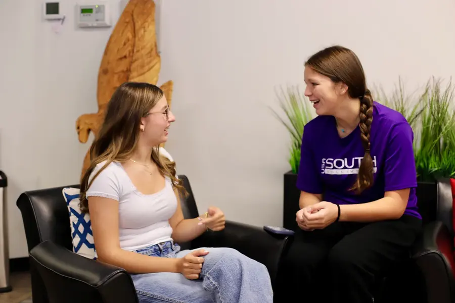 Two students in conversation in a campus lounge